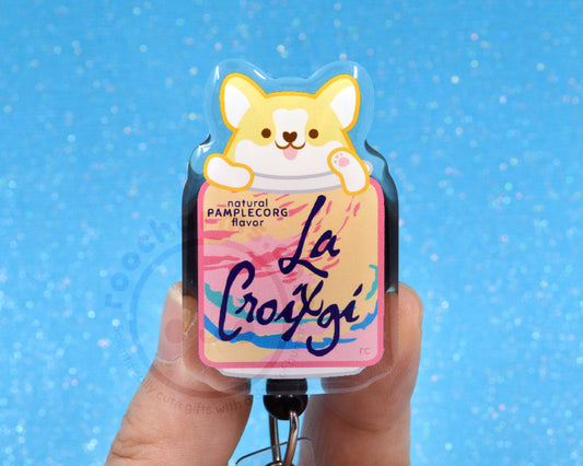 A person's hand holding a keychain with a label that features a cartoon image of a dog and text that says "La Croxigi" in a pink and yellow color scheme.