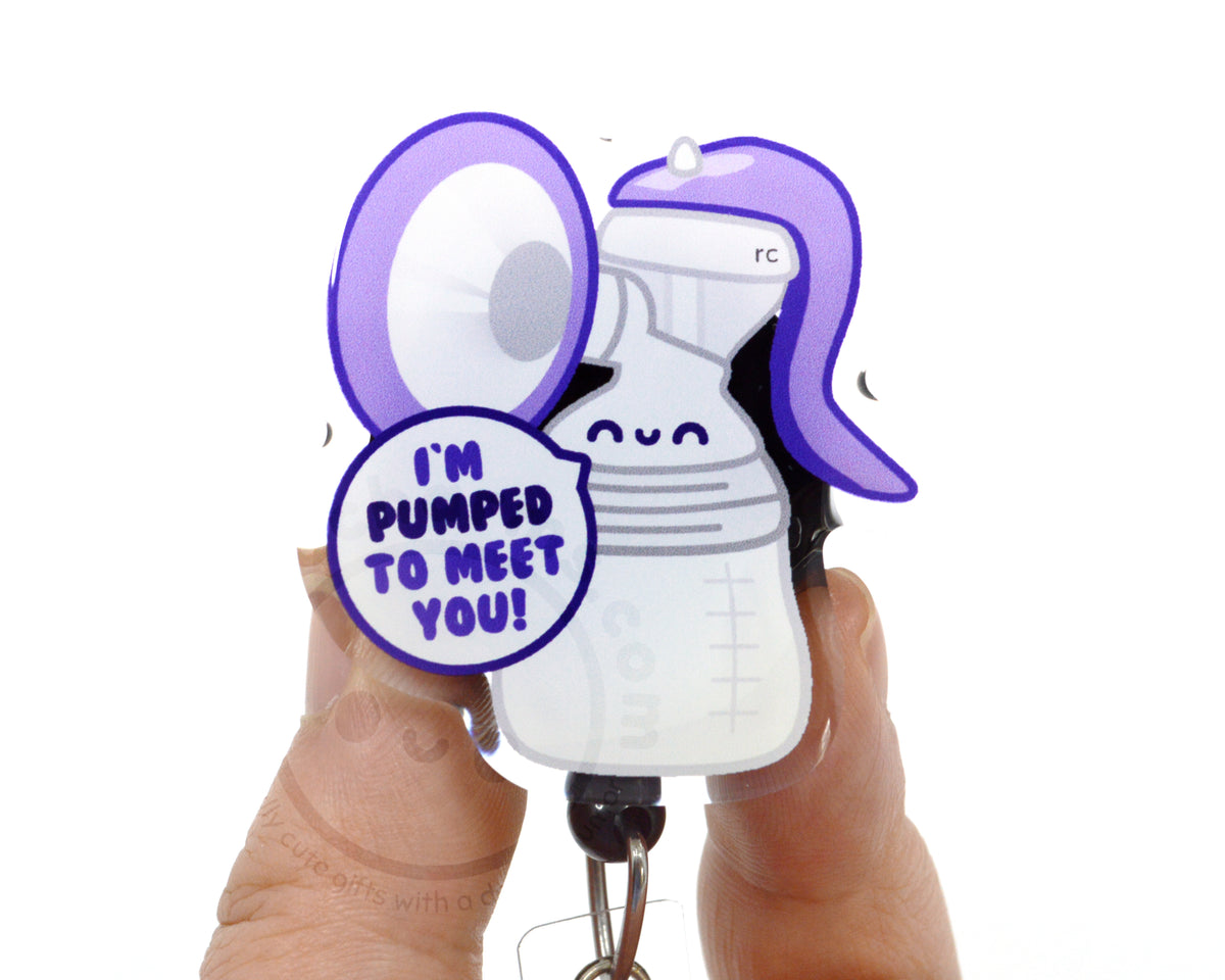 A person's hands holding a keychain with a cartoon image of a bottle and a speech bubble saying "I'm PUMPED TO MEET YOU!"
