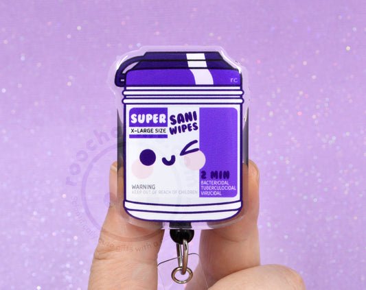 A hand holding a keychain with a purple and white design, featuring a cartoon character and text.