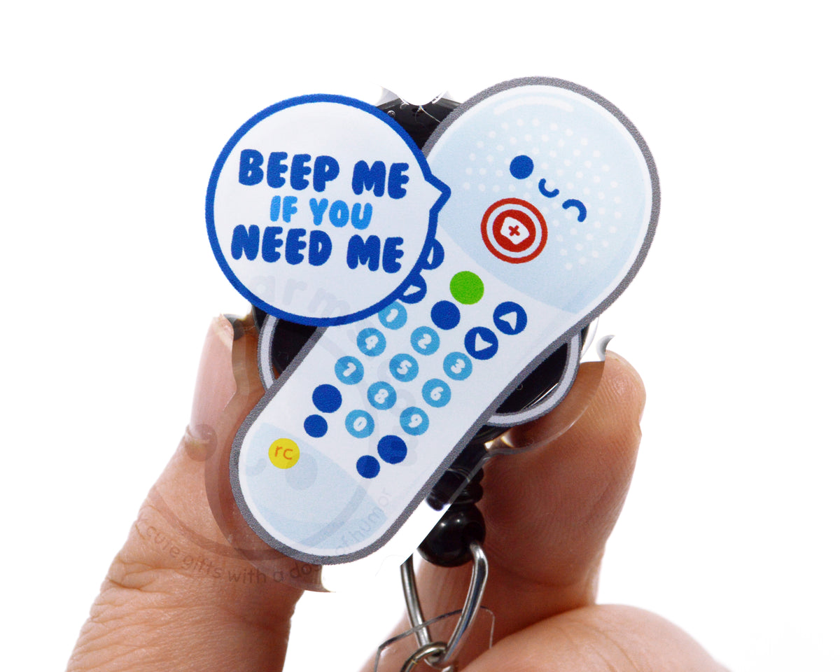 A person's hand holding a keychain with a remote control and a speech bubble containing the text "Beep me if you need me".